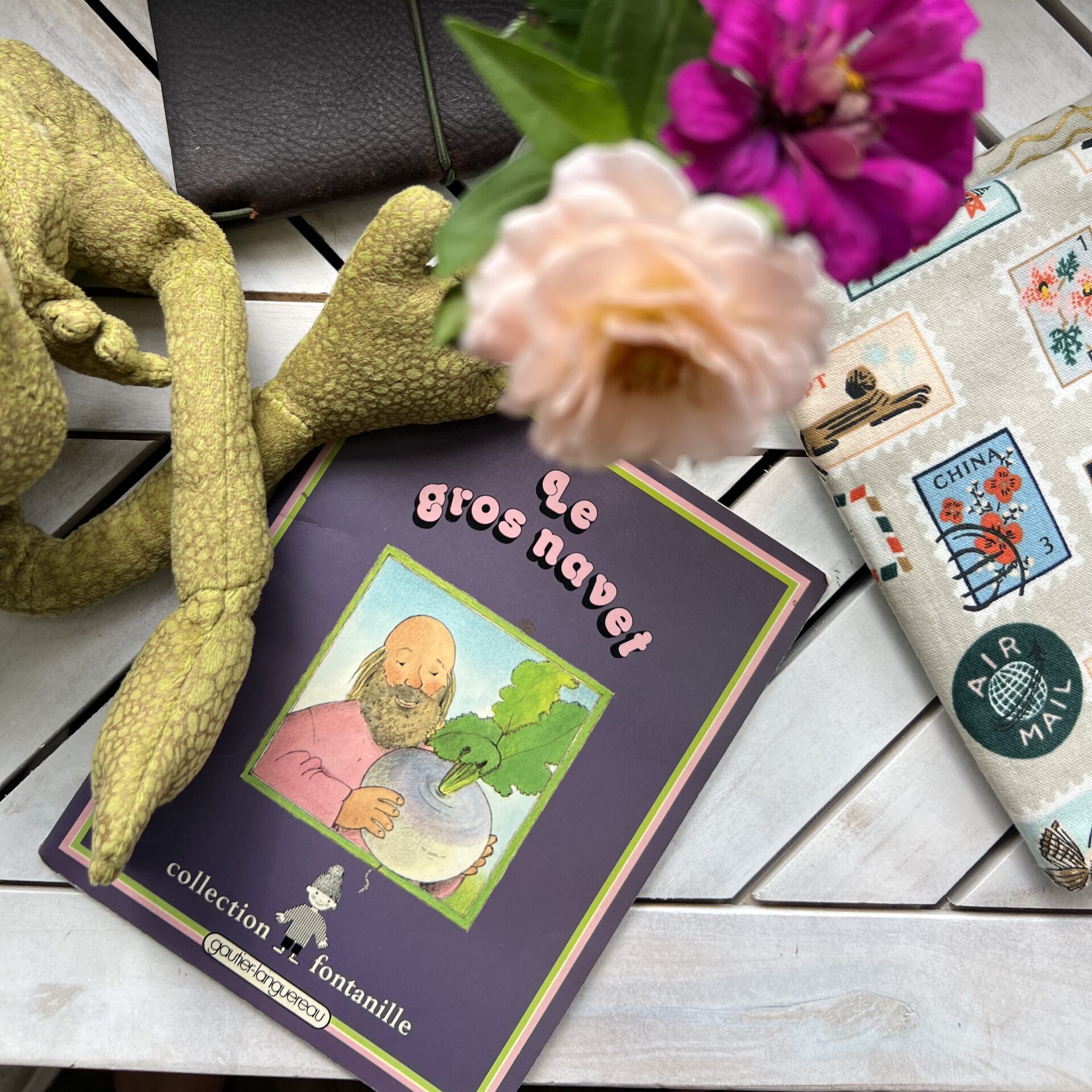 French children's book Le gros navet on a table with flowers, a stuffed toy, and stationery.